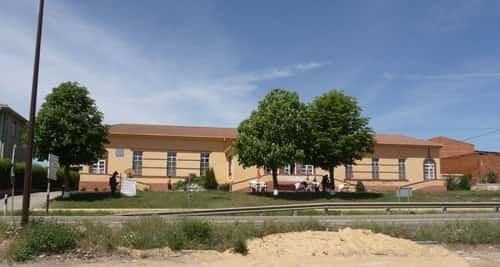 Albergue de Villadangos del Páramo, com algumas árvores na frente fazendo sombra e algumas cadeiras para os peregrinos sentarem.