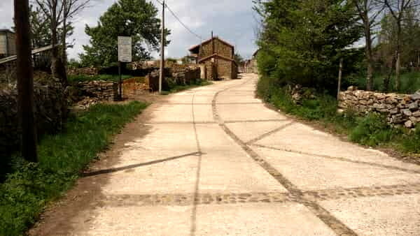 A foto mostra o caminho de cimento na entrada de Rabanal del Camino. Esta é a entrada do pueblo. Ao fundo as primeiras construções do lugar.