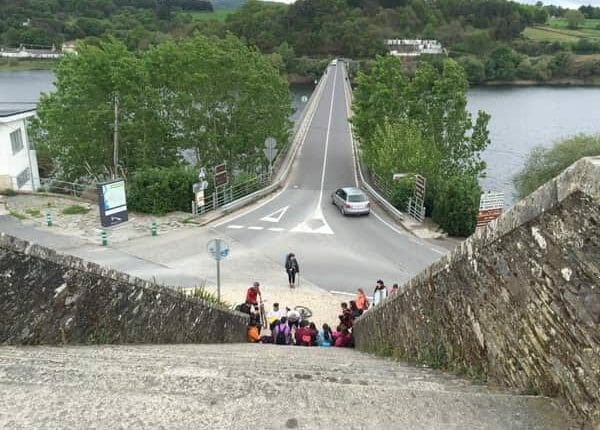 A foto, tirada da parte de cima da escadaria, mostra a escadaria e a ponte da chegada em Portomarín.